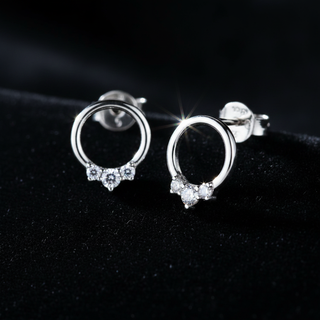 14K white gold three-diamond open circle stud earrings on dark moody background