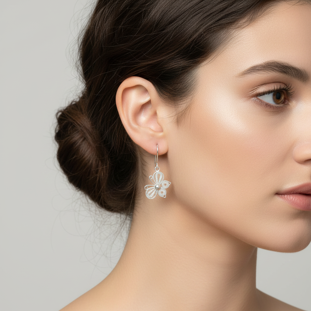 Sterling silver filigree butterfly drop earrings worn on model, butterflies hanging sideways in flight, true to scale lifestyle jewelry photography