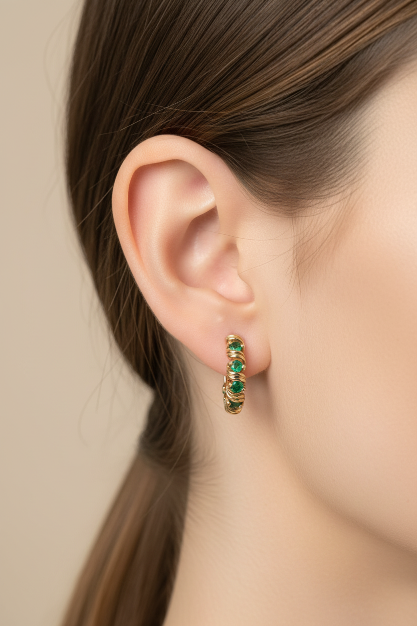 Model wearing 14K yellow gold J-hoop earrings with natural emeralds, true to life scale lifestyle shot