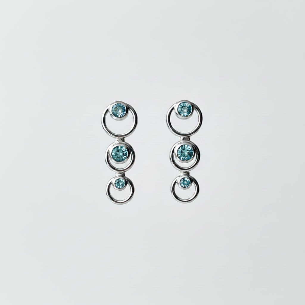 Blue topaz graduated circle drop earrings in 14kt white gold suspended on pure white background