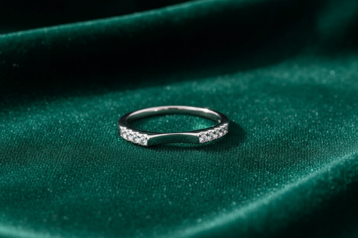 14K white gold curved diamond wedding band laying on bold emerald green velvet surface