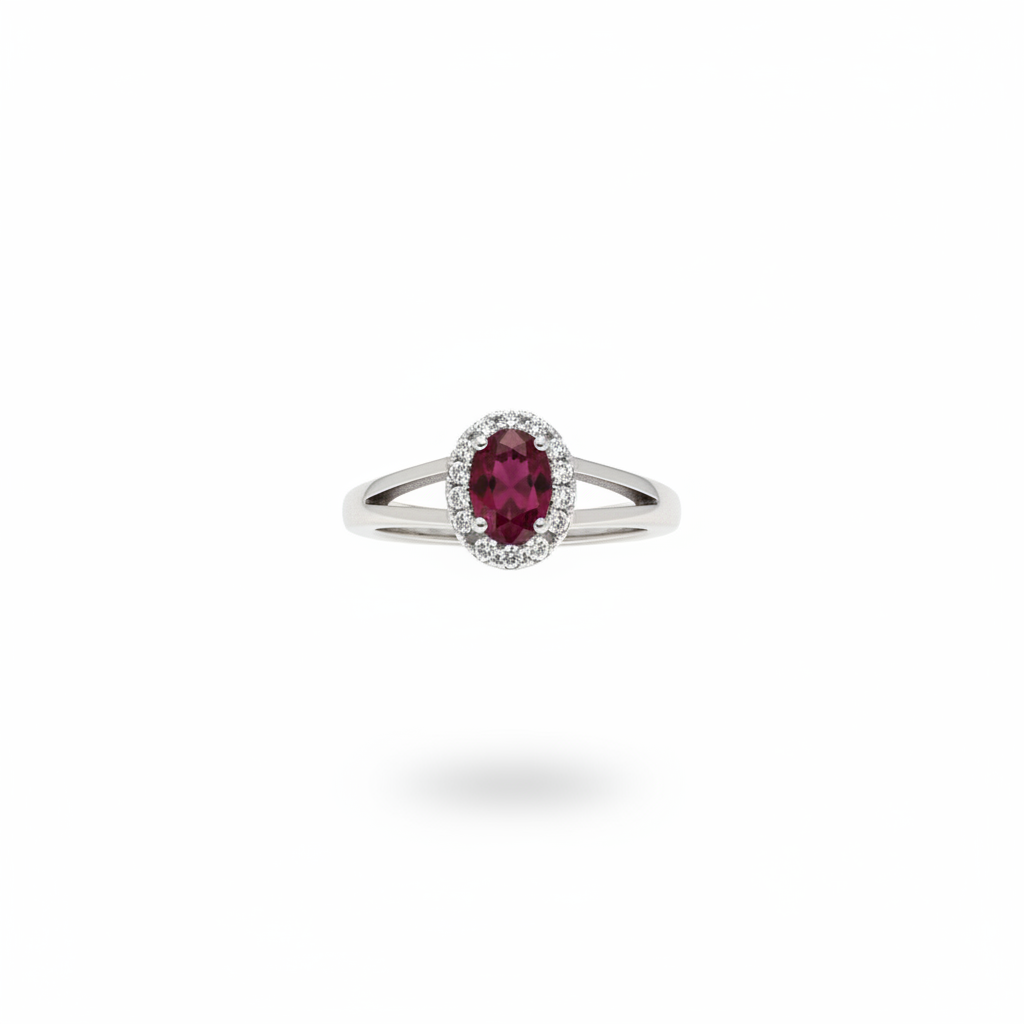 Oval ruby and diamond halo ring in 14kt white gold suspended on white background